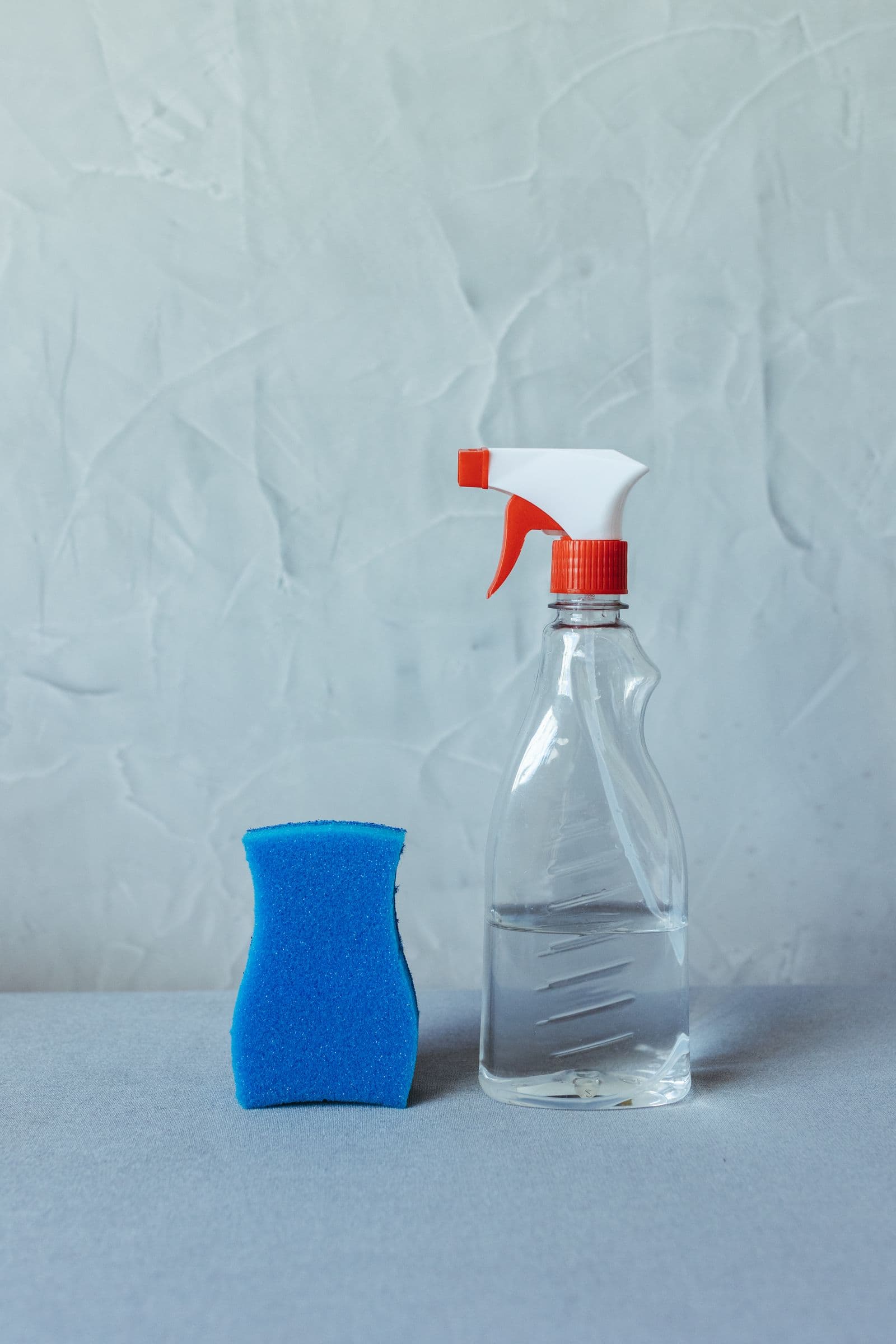 Clear spray bottle beside a blue sponge