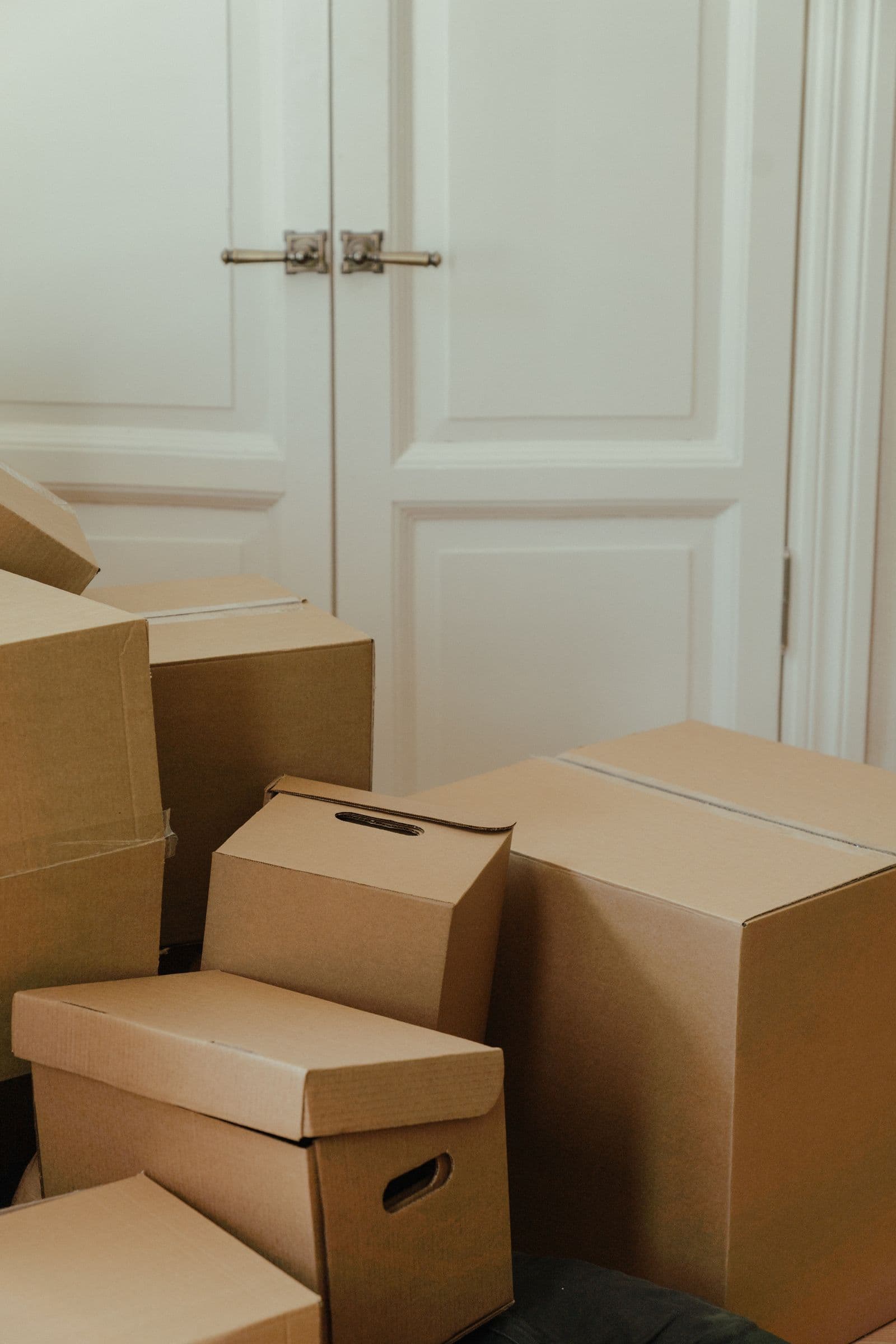 Cardboard boxes stacked beside a white door in an empty home