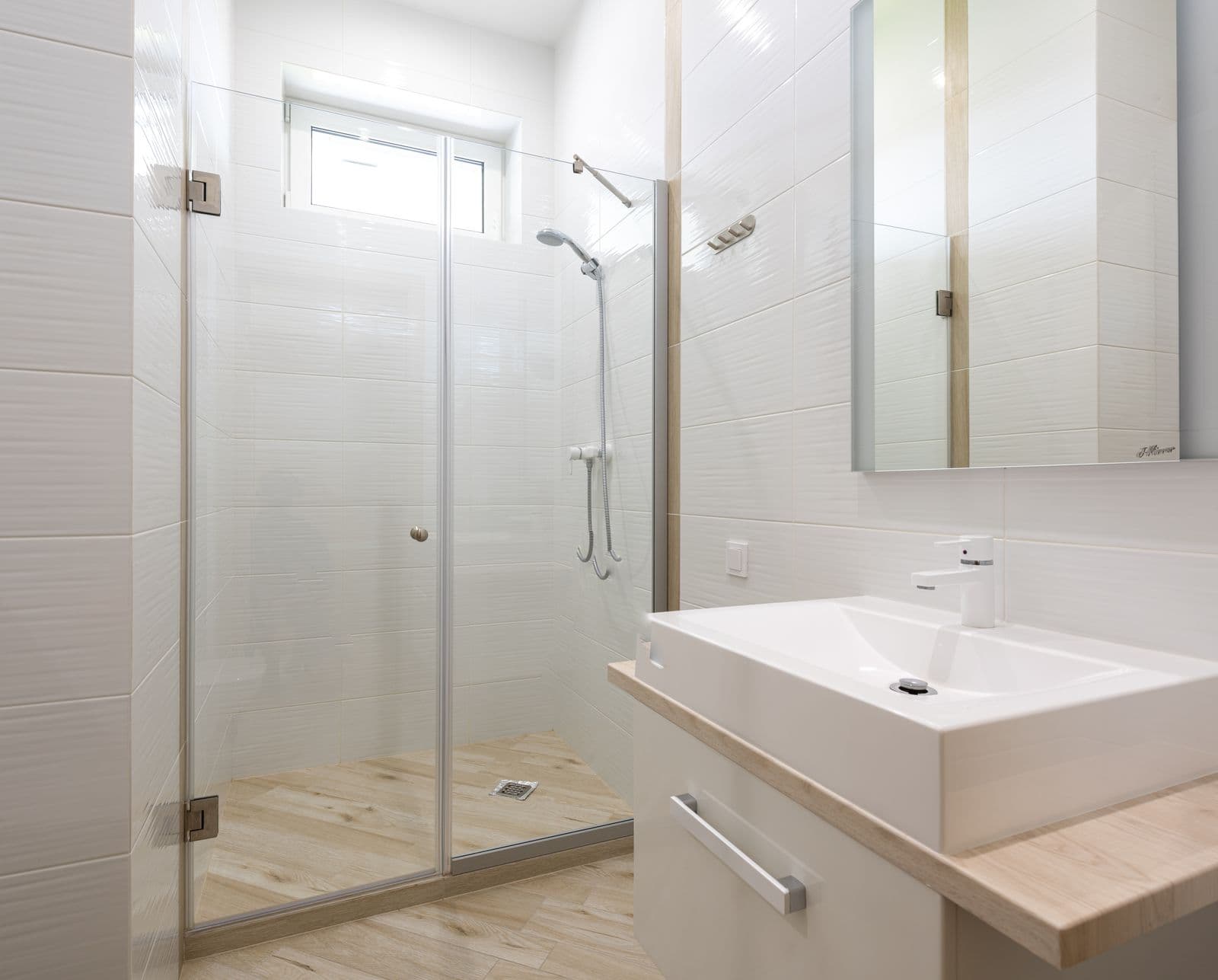 Clean white sink and glass shower cabin in a bathroom