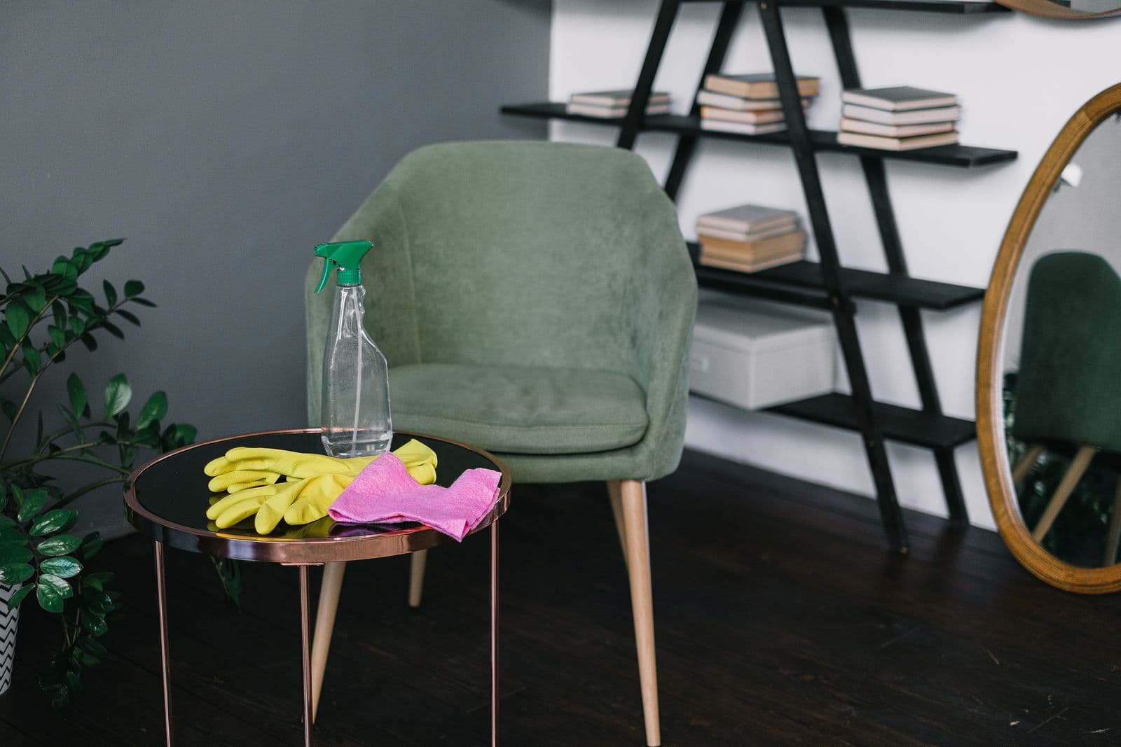 Yellow rubber gloves, a spray bottle and a cloth on a table in a tidy living room