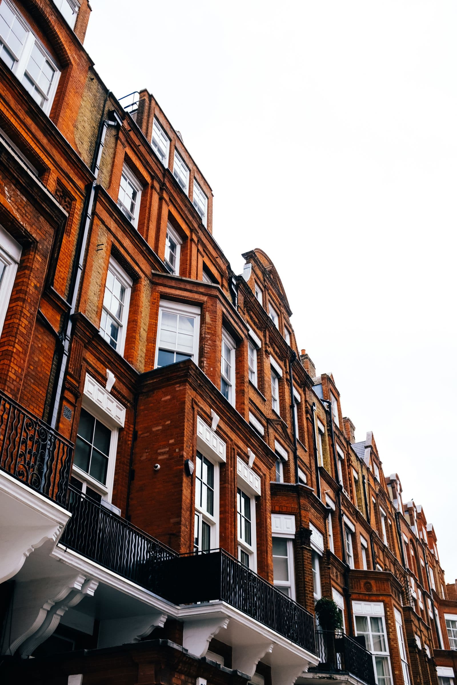 Brick terraced houses seen from below against a bright sky